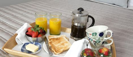 Un plateau de petit-déjeuner avec des toasts, des fruits, du jus, du café et un petit ramequin de beurre posé sur une serviette.