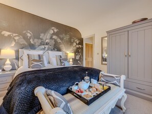 A hotel room with a bed, a breakfast tray, a wardrobe, and a wall with a floral mural. - 3 Bed in Leyburn (oc-g0133) (Preston-under-Scar)