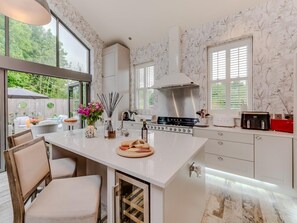 A modern kitchen with a large island, white cabinetry, and a view of the outdoors. - 3 Bed in Leyburn (oc-g0133) (Preston-under-Scar)