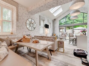 A spacious living area with a large window, a fireplace, and a dining table. - 3 Bed in Leyburn (oc-g0133) (Preston-under-Scar)
