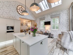 A spacious kitchen with a central island, white cabinetry, and a large window providing natural light. - 3 Bed in Leyburn (oc-g0133) (Preston-under-Scar)
