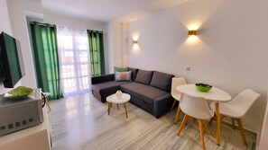 A modern living room with a sofa, a small round table, and a TV. - Sol Suites Apartment with a Balcony (Fuengirola)