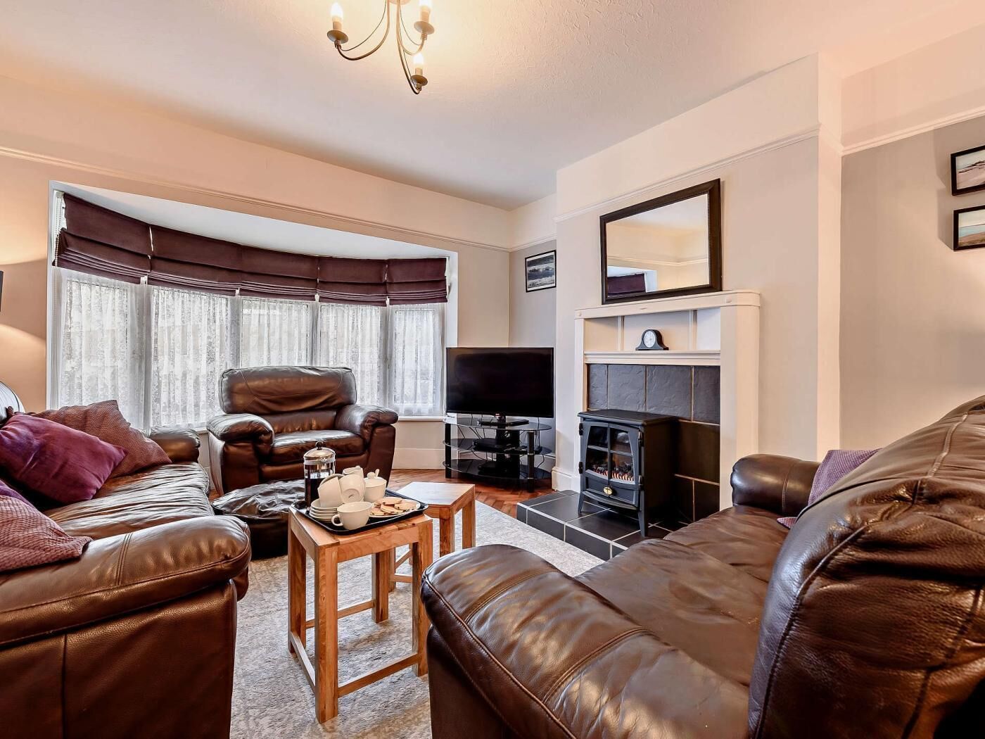 Una sala de estar con sofás de cuero, televisor, chimenea y una mesa de comedor con una bandeja de objetos.