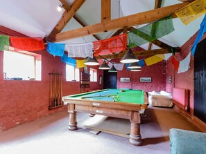 Ein Billardtisch in einem Raum mit Holzbalken, einem Billardständer und bunten Wimpeln.