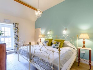 Ein Schlafzimmer mit einem Bett, Nachttischlampen, einem Chandelier und einem Fenster mit Vorhängen.