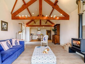 Ein Wohnzimmer mit einer Couch, einem Couchtisch mit Speisen, einem Kamin und einer Küche im Hintergrund.