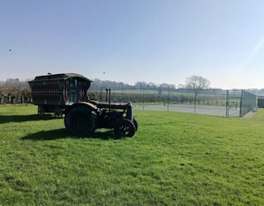 Un tractor a un camp amb una remolc verda i una zona tancada al fons.