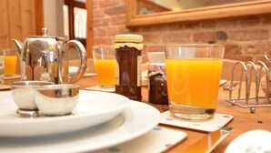 Ein Frühstückstisch mit Teekanne, Zuckerdose und einem Glas Orangensaft.
