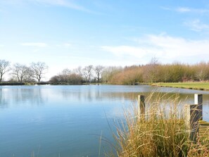 A calm lake with trees and a grassy area in the background. - 2 Bed in Market Rasen (oc-73853) (East Barkwith)