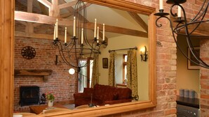 Ein Ziegelraum mit einem großen Spiegel, der ein Wohnzimmer, einen Kamin und eine Waschmaschine reflektiert.