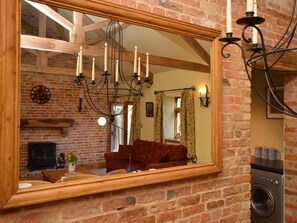 A brick interior with a large mirror reflecting a living room, a fireplace, and a washing machine. - 2 Bed in Market Rasen (oc-73853) (East Barkwith)