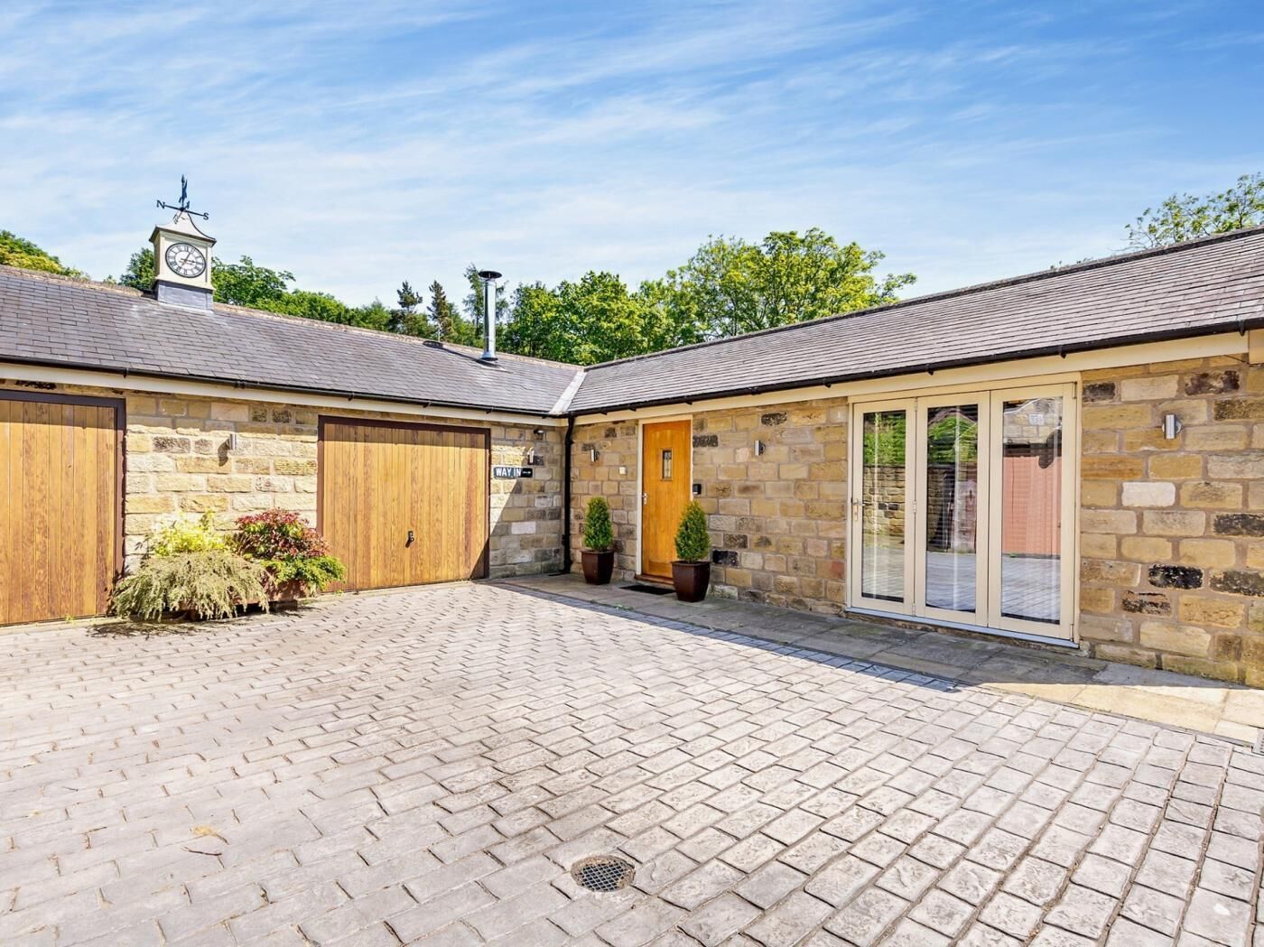 Un bâtiment en pierre avec une porte en bois et une cour intérieure pavée de briques.