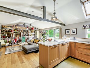 A spacious kitchen with wooden cabinets, a central island, and a large window providing a view of greenery. - 2 Bed in Hampsthwaite (oc-g0156) (Clint)