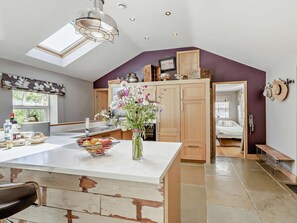 A kitchen with a central island, wooden cabinets, a skylight, and a view into a bedroom. - 2 Bed in Hampsthwaite (oc-g0156) (Clint)