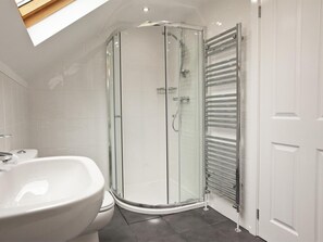 Ein modernes Badezimmer mit einer Duschkabine aus Glas, einem weißen Waschbecken und einem Handtuchhalter.