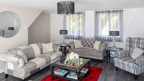 Un salon avec un canapé, des fauteuils, une table basse et un tapis rouge.