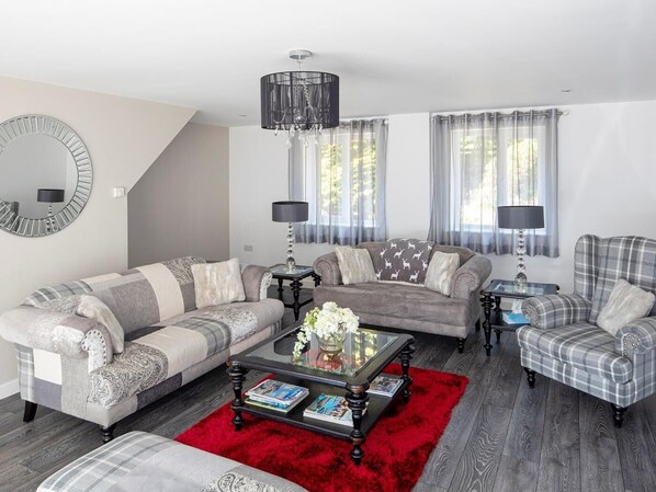 Ein Wohnzimmer mit einer Couch, Sesseln, einem Couchtisch und einem roten Teppich.