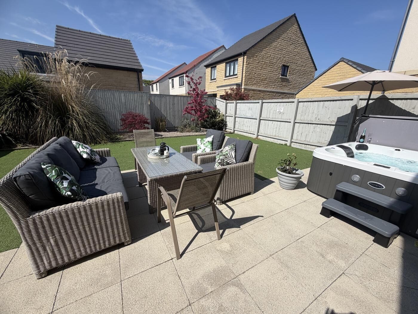 Un espace patio aménagé avec du mobilier d’extérieur, un jacuzzi et un petit jardin.