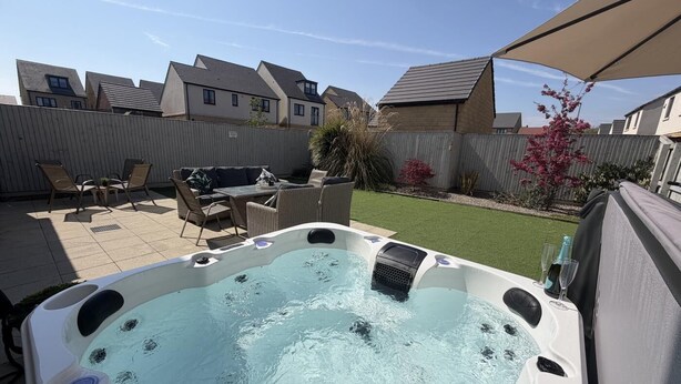 Ein Garten mit Whirlpool, Gartenmöbeln und einem eingezäunten Bereich.