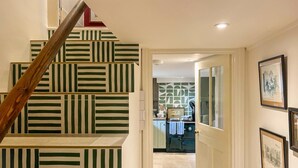 Una escalera con patrones a rayas, una cocina con un salpicadero decorado y cuadros en la pared.