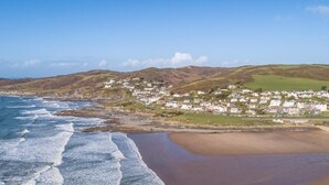 A coastal town with a beach, waves, and houses. - 3 Bed in Woolacombe (oc-74255) (Woolacombe)