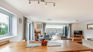 A modern kitchen with a wooden countertop, a fruit bowl, and a dining area with a table and chairs. - 3 Bed in Woolacombe (oc-74255) (Woolacombe)