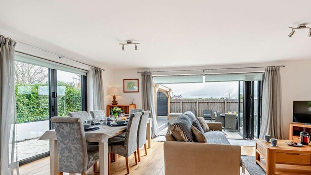 A spacious living area with a dining table, sofa, and TV stand. - 3 Bed in Woolacombe (oc-74255) (Woolacombe)