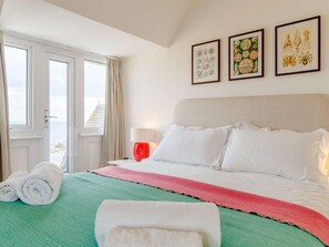 Ein Hotelzimmer mit einem Bett, einem Fenster mit Vorhängen und drei gerahmten Pflanzenbildern an der Wand.