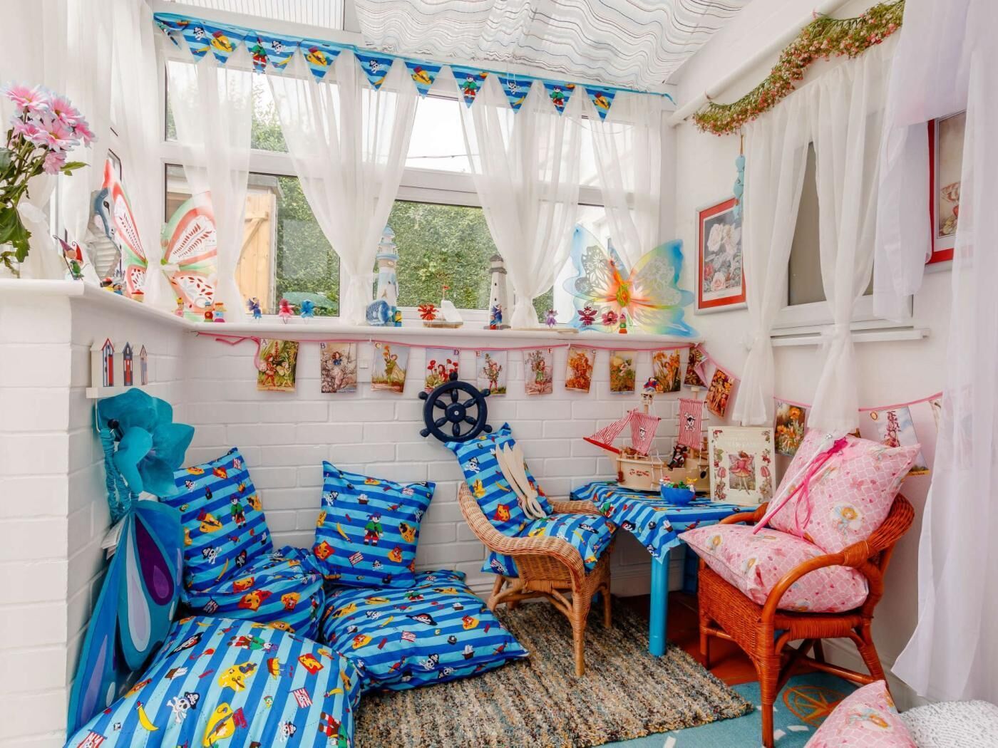 Een knus vertrek met een raam, een bed met blauw gestreepte lakens, een rieten stoel en een kleine tafel.