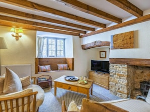 A cozy room with exposed wooden beams, a stone fireplace, a television, and a window with a view. - 2 Bed in Bridport (oc-dc148) (Burton Bradstock)