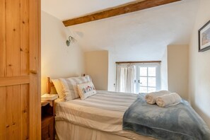 A bedroom with a bed, pillows, a window, and a wooden door. - 2 Bed in Bridport (oc-dc148) (Burton Bradstock)