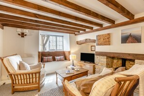 A cozy living room with a fireplace, wooden beams, a comfortable sofa, and a television. - 2 Bed in Bridport (oc-dc148) (Burton Bradstock)