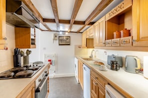 A kitchen with wooden cabinets, a stove, a sink, and a toaster. - 2 Bed in Bridport (oc-dc148) (Burton Bradstock)