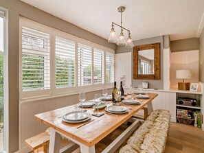 A dining area with a wooden table set for four, a bench, and a mirror above the table. - 4 Bed in Dorchester (oc-dc149) (West Bexington)
