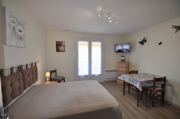 Une chambre à coucher avec un lit, un bureau, une chaise, une télévision et une fenêtre.