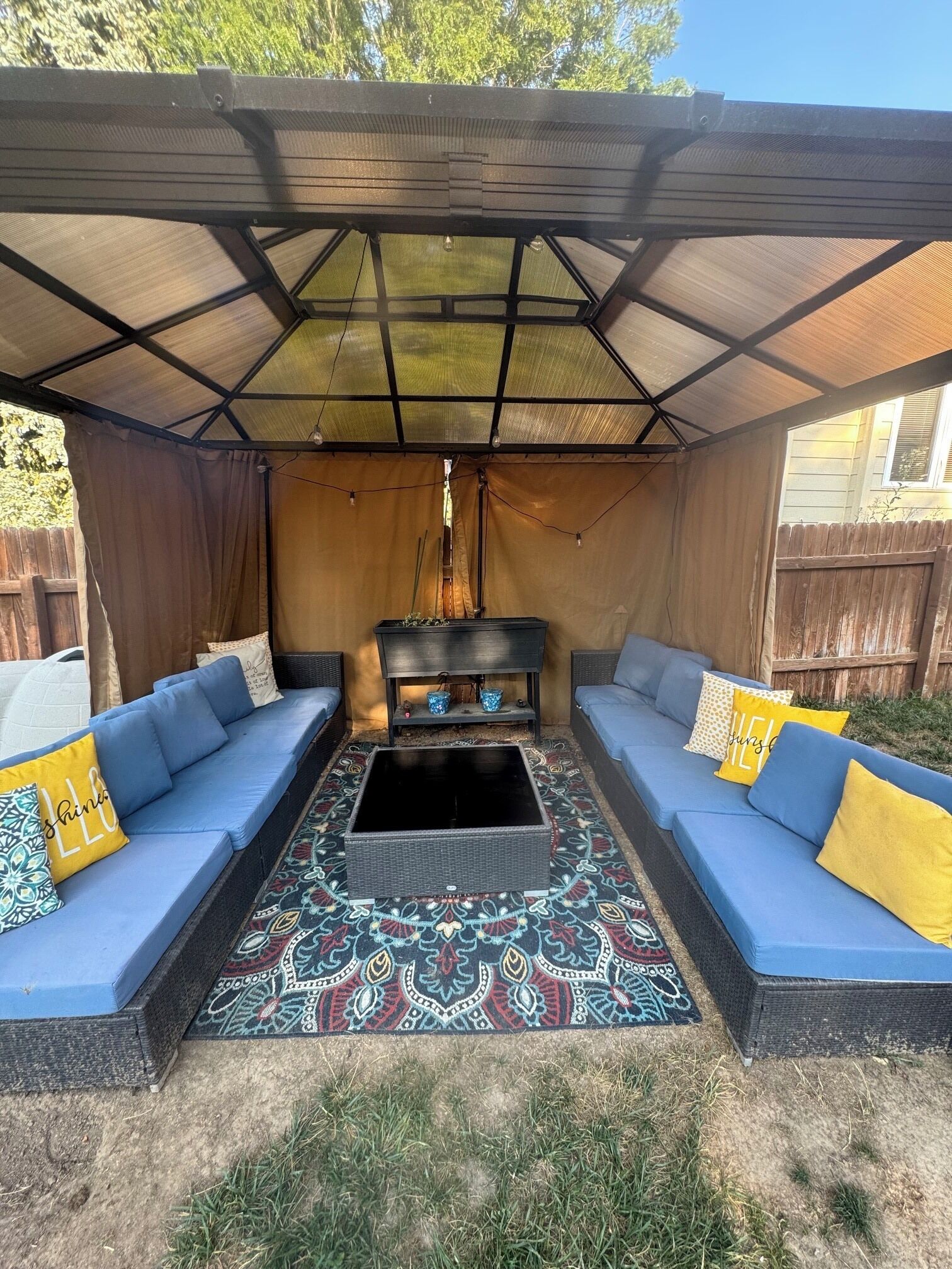 An outdoor seating area with two sofas, a coffee table, and a patterned rug.