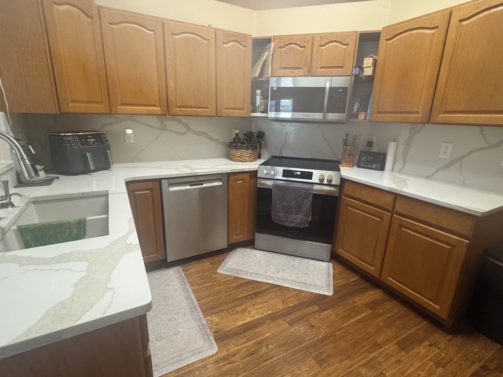 A kitchen with wooden cabinets, a microwave, a dishwasher, a stove, and a sink.