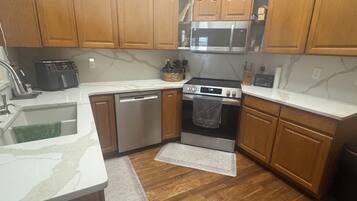 A kitchen with wooden cabinets, a microwave, a dishwasher, a stove, and a sink.