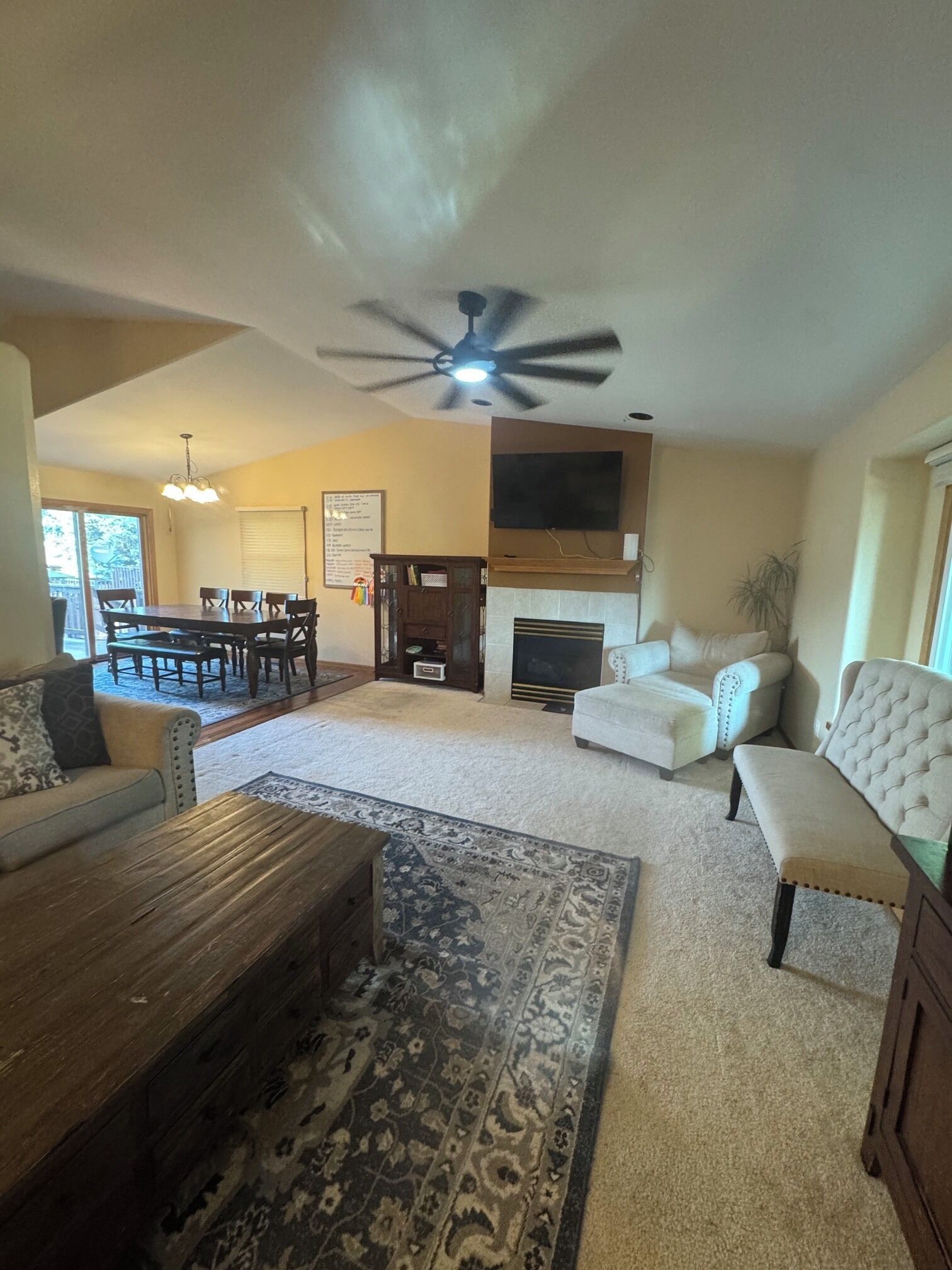 A living room with a fireplace, a ceiling fan, a dining table, and a sofa.
