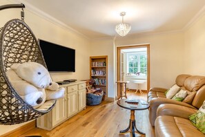 Ein Wohnzimmer mit Hängekorbschaukel, Sofa, Couchtisch, Bücherregal und Fernseher.