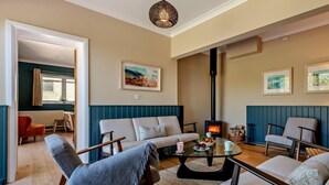 Una sala de estar con sofá, sillones, una mesa de centro, chimenea y obras de arte en las paredes.