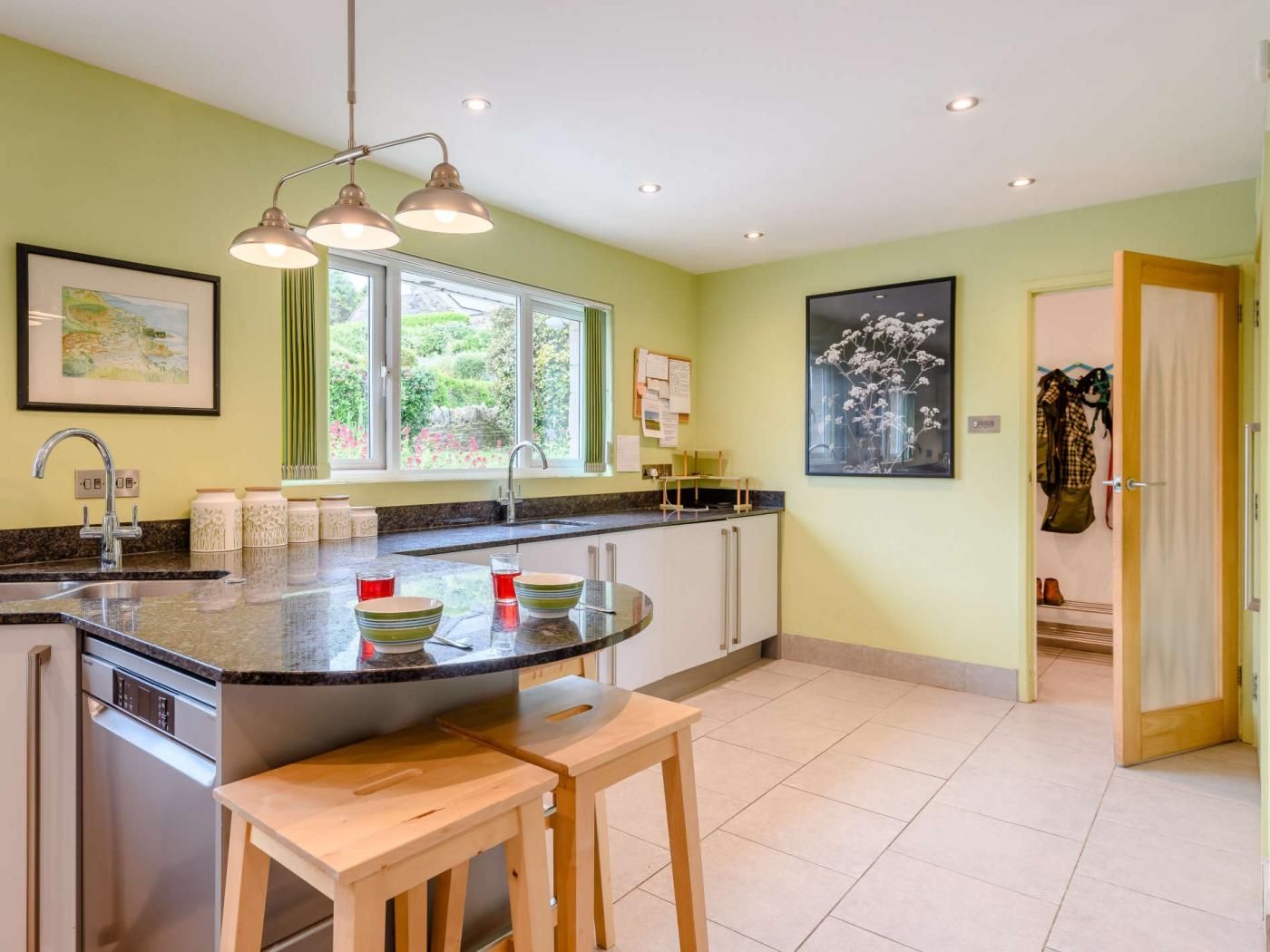 A kitchen with a central island, a sink, and a window overlooking a garden.