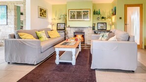 A living room with a fireplace, two sofas, a coffee table, and a rug. - 3 Bed in Swanage (oc-dc140) (Worth Matravers)