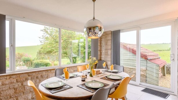 A dining area with a table set for four, large windows, and a view of the outdoors. - 3 Bed in Swanage (oc-dc140) (Worth Matravers)