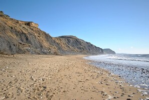A beach with a rocky shoreline and cliffs in the background. - 3 Bed in Bridport (oc-dc117) (West Bay)