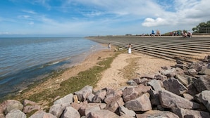 Eine Küstenlandschaft mit felsigem Ufer, blauem Himmel und ruhiger See.