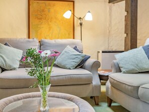 A living room with two sofas, a round coffee table, and a vase with flowers. - 2 Bed in Wasdale (oc-sz053) (Wasdale)