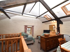 A cozy attic room with a sloped ceiling, wooden beams, a bed, a table, and a radiator. - 2 Bed in Wasdale (oc-sz053) (Wasdale)