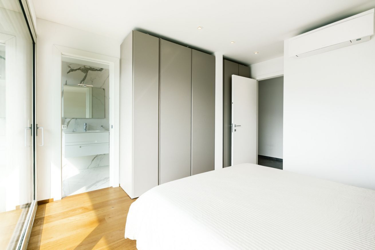 A bedroom with a bed, a wardrobe, and a bathroom with a mirror and sink.