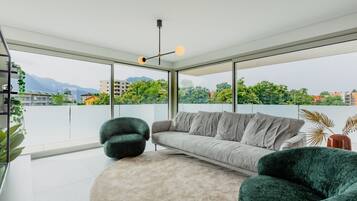 Ein modernes Wohnzimmer mit einer Couch, zwei Sesseln, einem runden Teppich und einer Deckenleuchte.